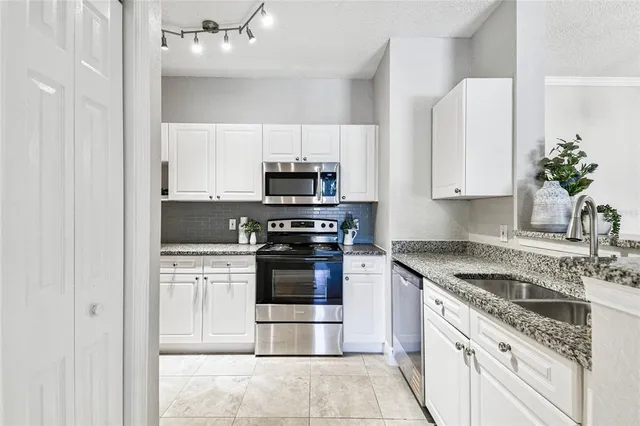 a kitchen with kitchen island granite countertop white cabinets and stainless steel appliances