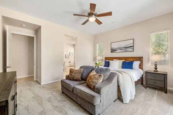 a spacious bedroom with a bed a couch and a ceiling fan