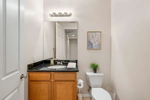 a bathroom with a granite countertop sink and a toilet