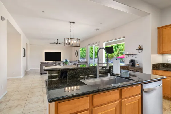 a kitchen with kitchen island granite countertop a sink appliances and cabinets