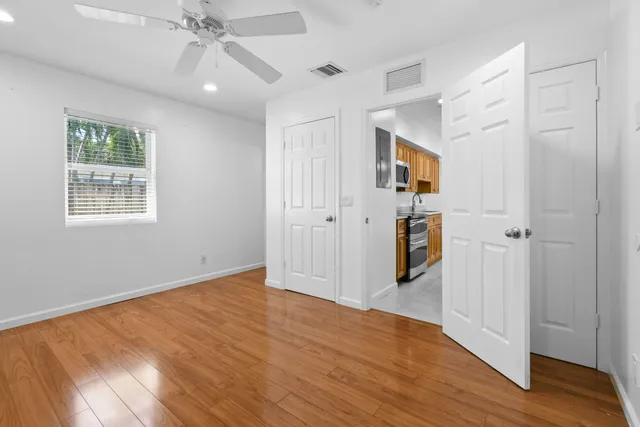 a view of an empty room with wooden floor and a window