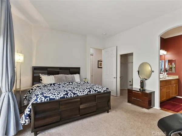 a bedroom with a bed a mirror and a lamp on dresser