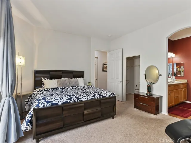 a bedroom with a bed a mirror and a lamp on dresser