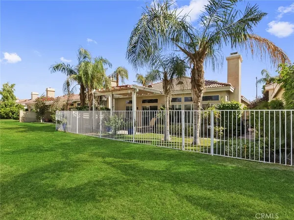 a view of a house with a big yard and palm trees
