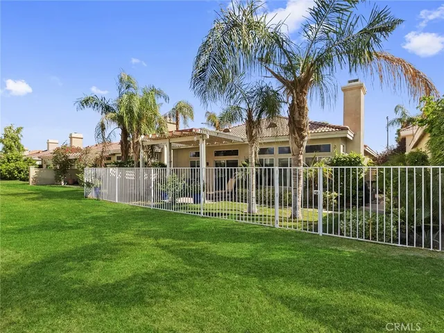 a view of a house with a big yard and palm trees