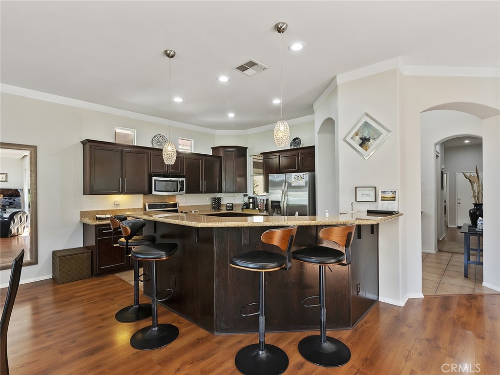 48957 Heifitz Drive Indio, CA 92201 - Photo 8 of 34 a kitchen with stainless steel appliances granite countertop a refrigerator a stove a sink a dining table and chairs with wooden floor