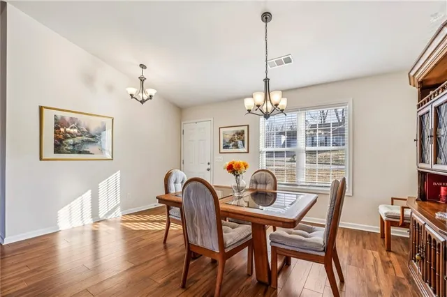 a dining room with furniture a chandelier and wooden floor
