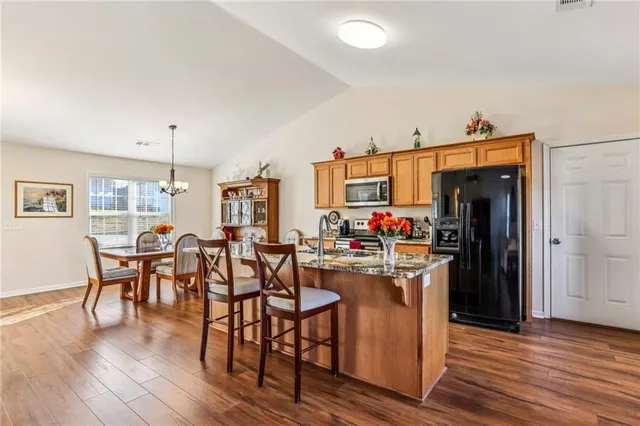 a kitchen with stainless steel appliances a dining table chairs stove and refrigerator