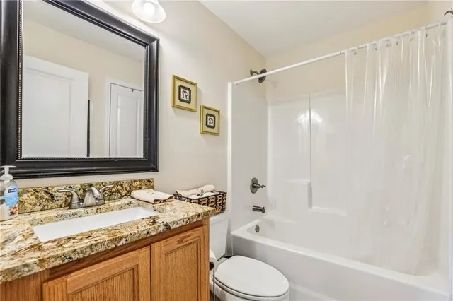 a bathroom with a granite countertop sink toilet and shower