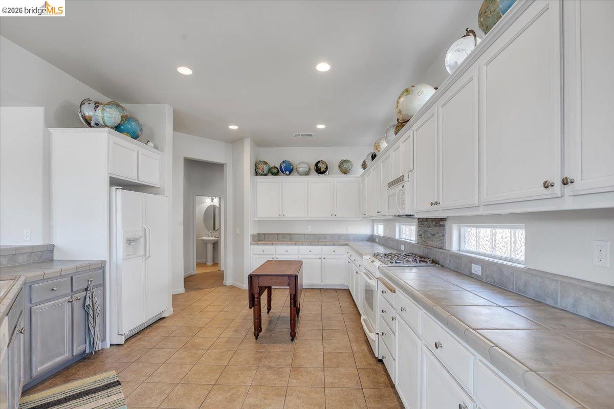 258 Rock Ridge Lane Copperopolis, CA 95228 - Photo 17 of 47 Kitchen with tile counters, white appliances, recessed lighting, white cabinets, and light tile patterned floors