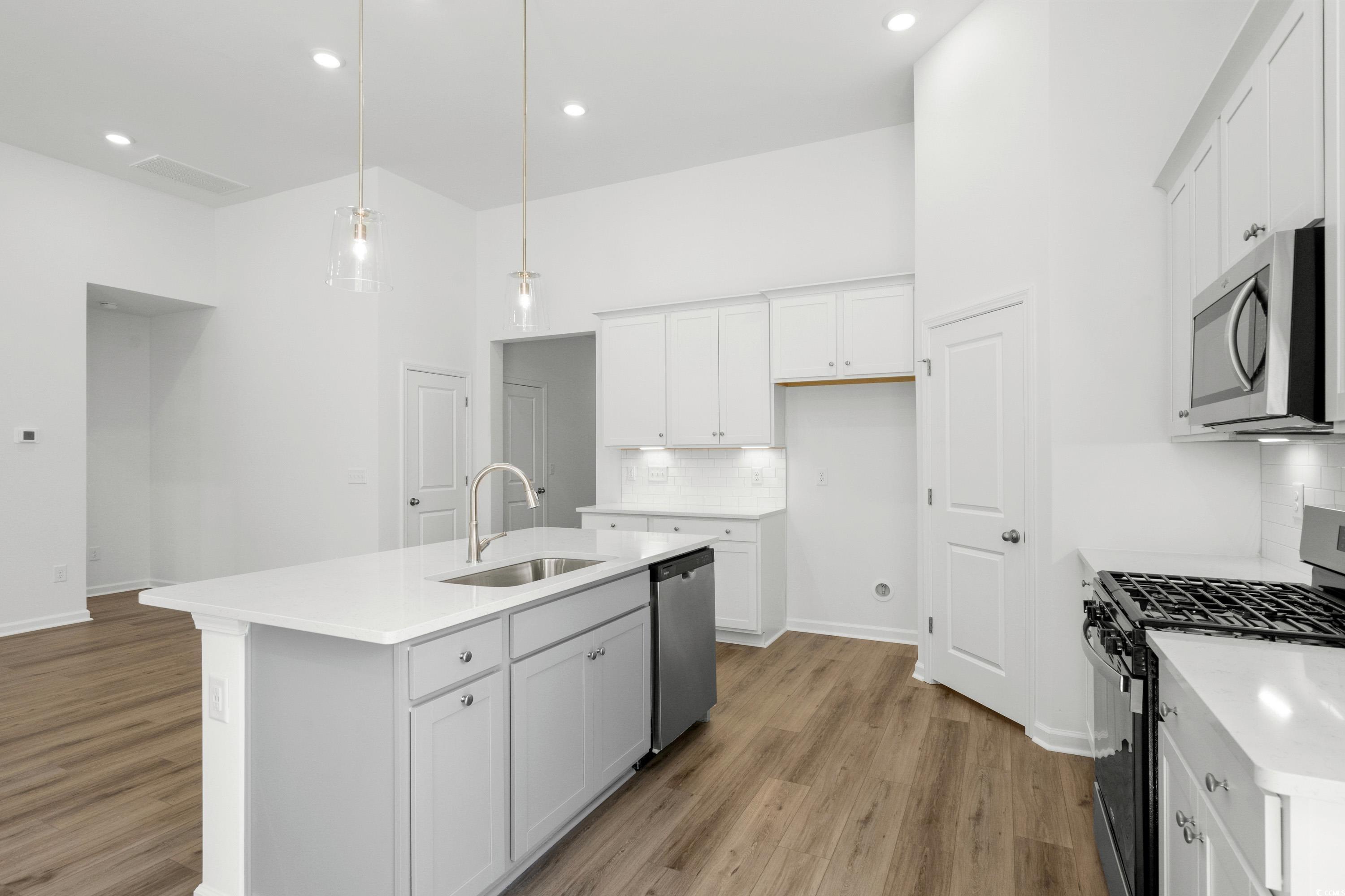 444 Sun Colony Boulevard Longs, SC 29568 - Photo 11 of 31 Kitchen featuring stainless steel gas appliances, upgraded white cabinets with crown molding, quartz countertops, pendant lighting and brushed satin nickel fixtures.