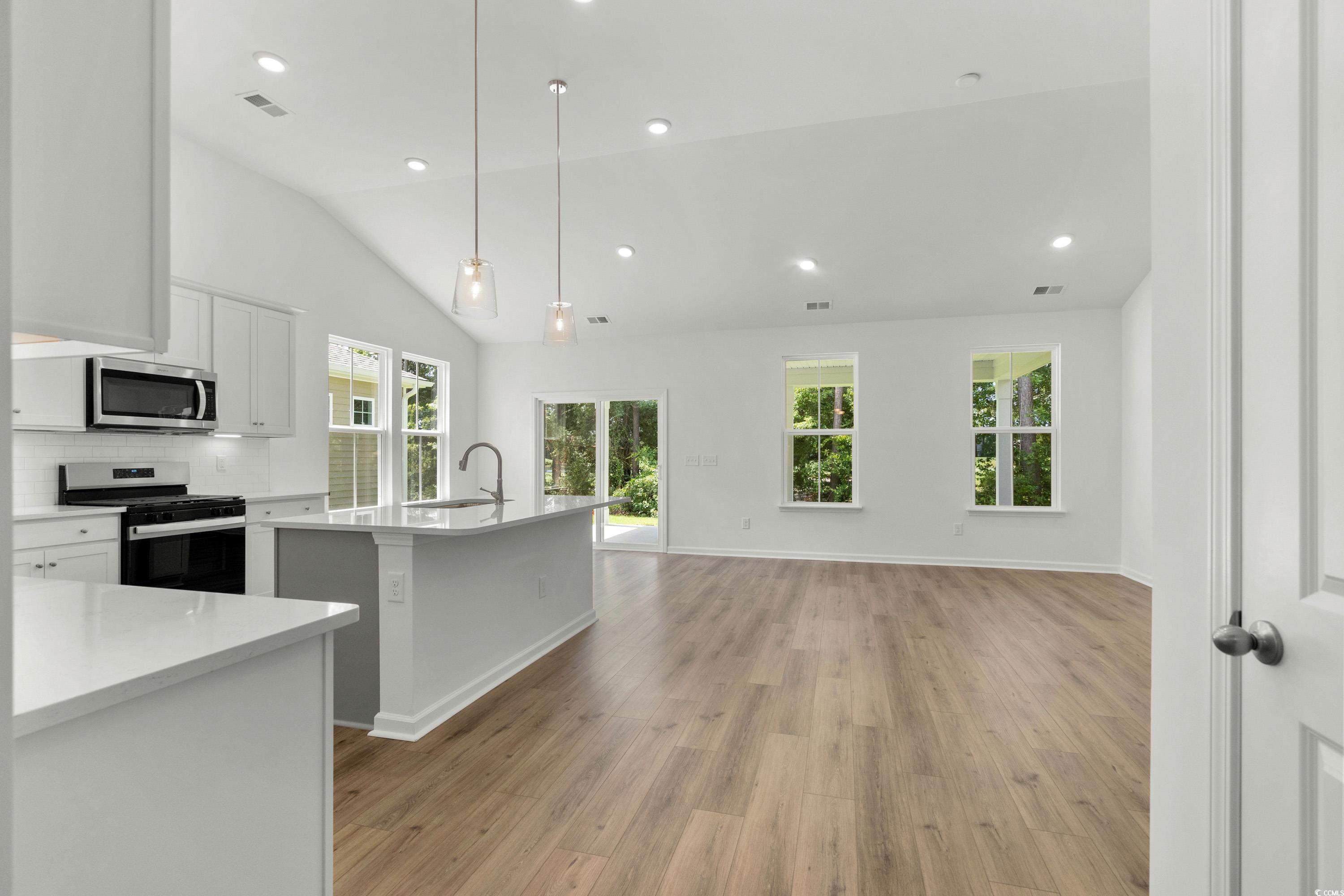 444 Sun Colony Boulevard Longs, SC 29568 - Photo 5 of 31 Open concept kitchen, dining and living area featuring 6ft windows, 12ft vaulted ceiling, and LVP throughout the entire homes.