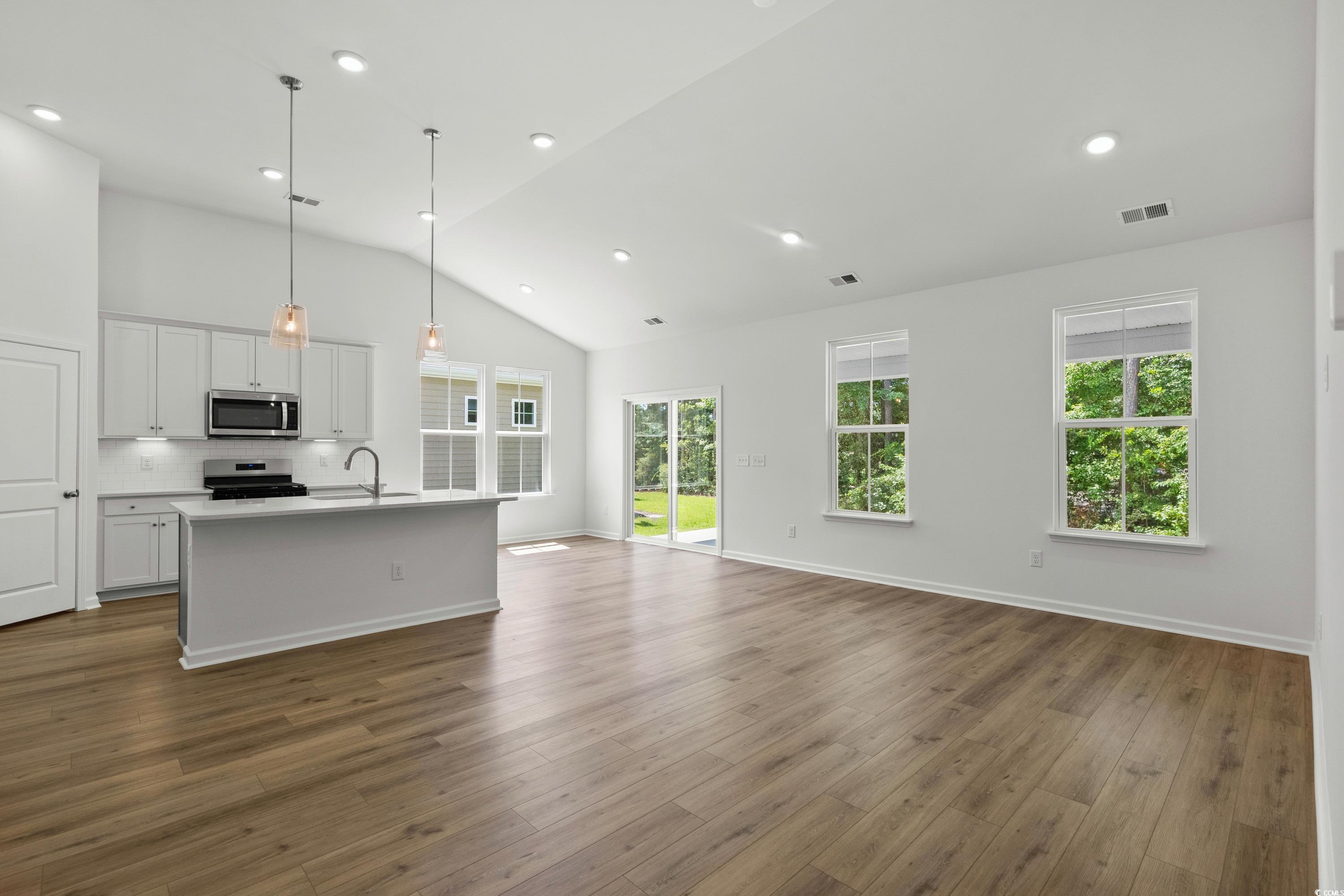 444 Sun Colony Boulevard Longs, SC 29568 - Photo 6 of 31 Open concept kitchen, dining and living area featuring 6ft windows, 12ft vaulted ceiling, and LVP throughout the entire homes.