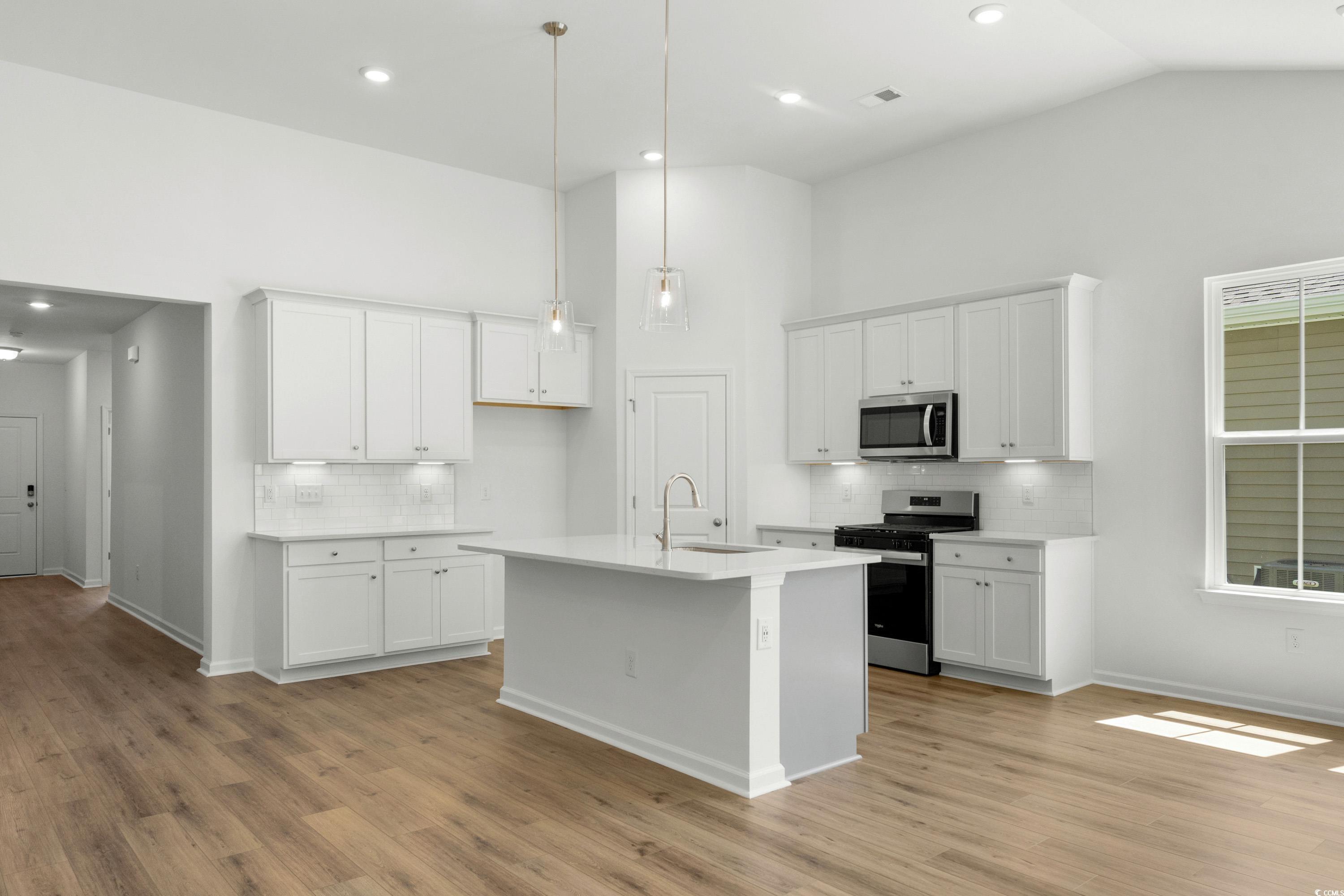 444 Sun Colony Boulevard Longs, SC 29568 - Photo 9 of 31 Kitchen featuring stainless steel gas appliances, upgraded white cabinets with crown molding, quartz countertops, pendant lighting and brushed satin nickel fixtures.