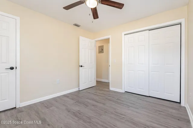 an empty room with wooden floor cabinet and windows
