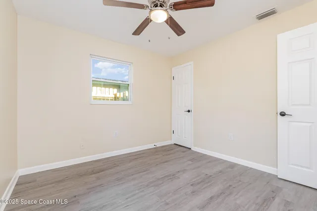 an empty room with a window and a ceiling fan