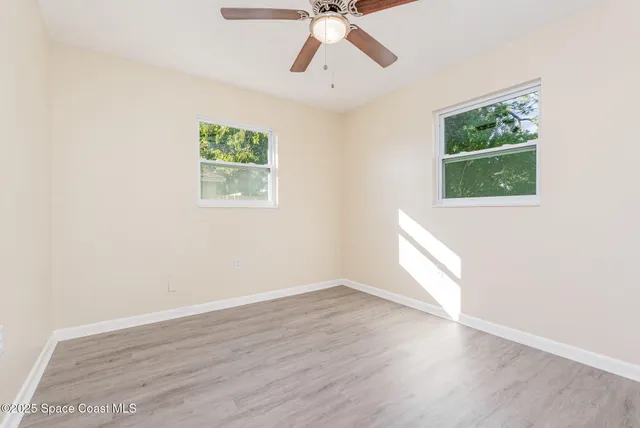 a view of an empty room with wooden floor and window