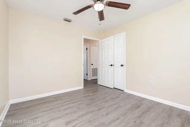 an empty room with wooden floor ceiling fan and window