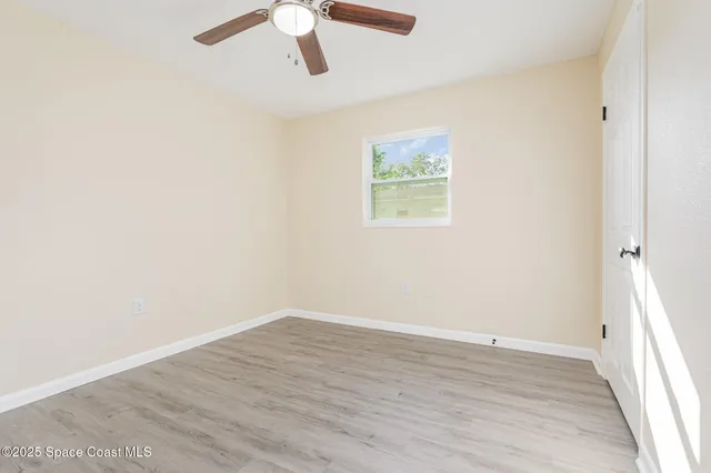 an empty room with a window and a ceiling fan