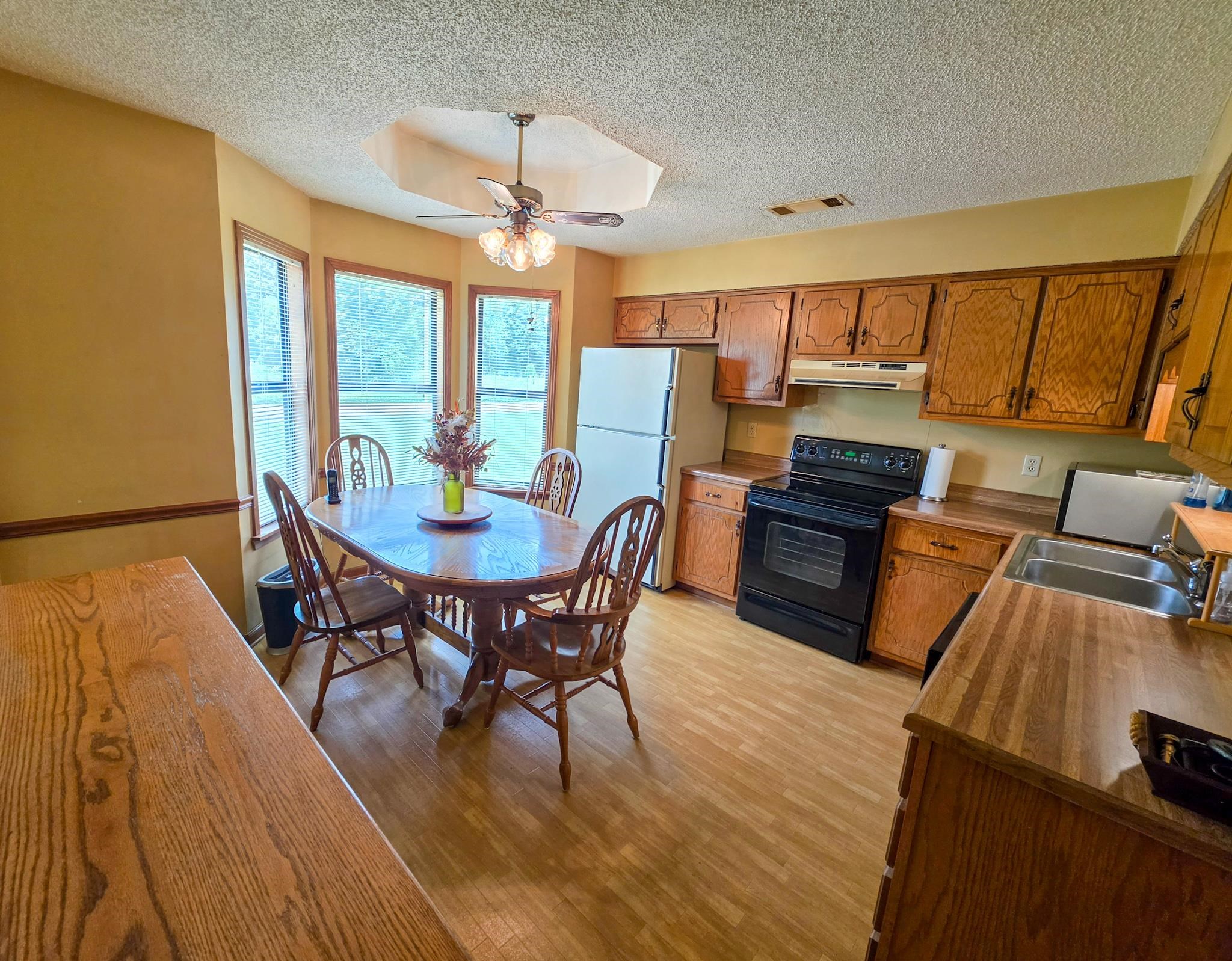 966 Beaver Road Munford, TN 38058 - Photo 22 of 32 Kitchen featuring wood-finish flooring, wood cabinetry, laminate countertops, and a bay window with a ceiling fan