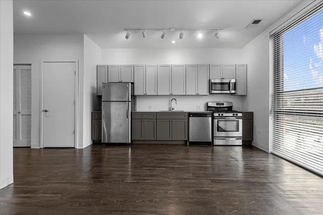 a kitchen with stainless steel appliances wooden floor and a refrigerator