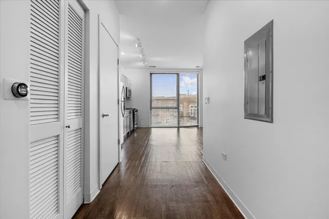 a view of a hallway with wooden floor and closet