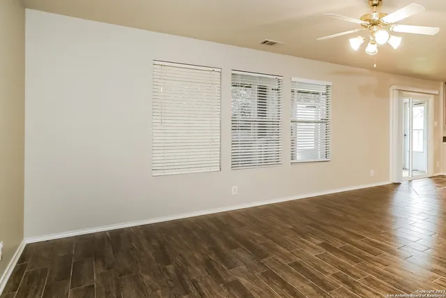 a view of an empty room with wooden floor and a window