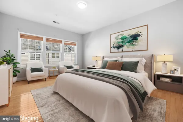 a bedroom with bed couches and large window