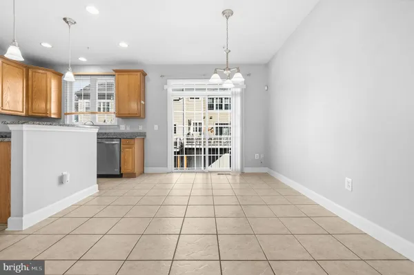 a view of an empty room with window and kitchen view