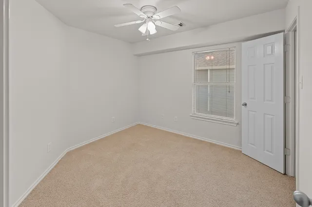 an empty room with closet and a chandelier fan