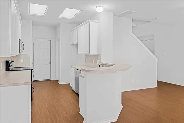 a view of a kitchen with a sink oven cabinets and wooden floor