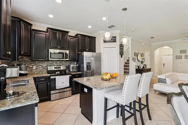 a kitchen with granite countertop a refrigerator a sink a stove and cabinets