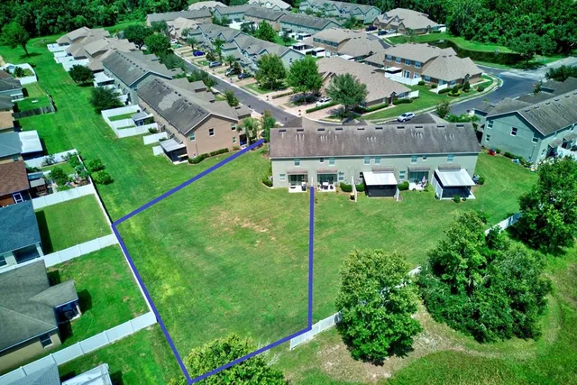 an aerial view of residential houses with outdoor space and trees