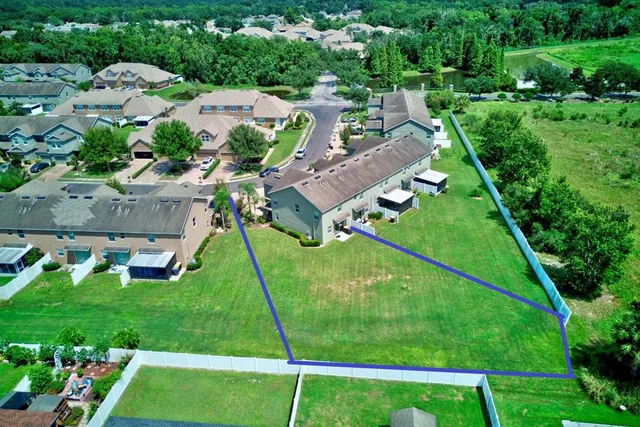 an aerial view of residential houses with outdoor space and trees