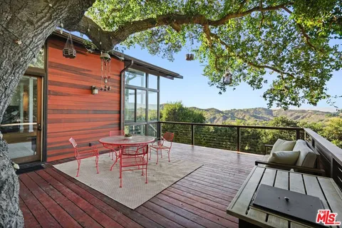 a balcony with wooden floor table and chairs