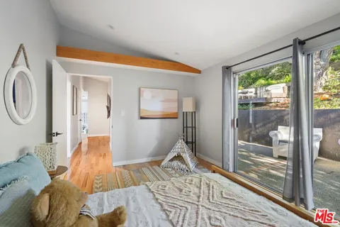 a view of a patio with couches and a large tree with wooden floor and fence