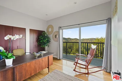 a balcony with table and chairs and potted plants