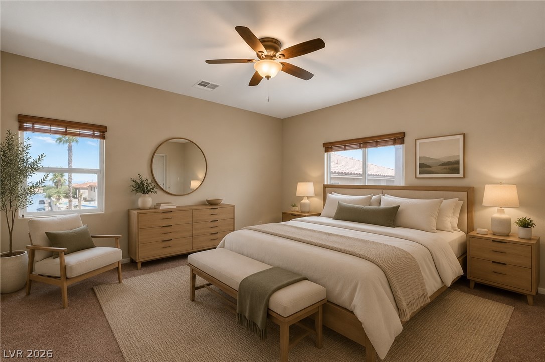 5014 Fiery Sky Ridge Street Las Vegas, NV 89148 - Photo 14 of 21 A well-lit primary bedroom offers plush carpeting and a modern ceiling fan, with ample natural light from two windows.