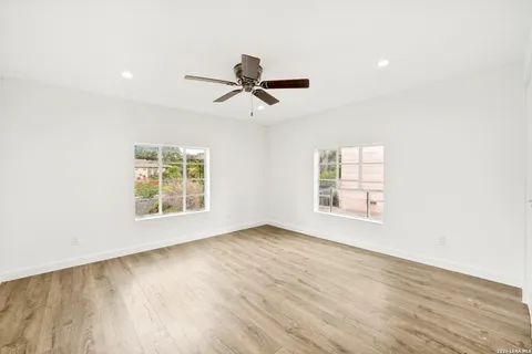 a view of empty room with wooden floor and fan