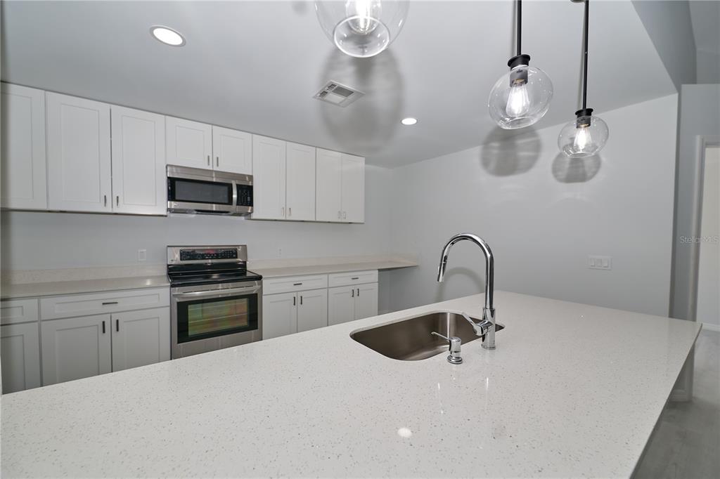 119 Ridgecrest Drive Eustis, FL 32726 - Photo 27 of 52 a kitchen with kitchen island granite countertop a sink stainless steel appliances and white cabinets