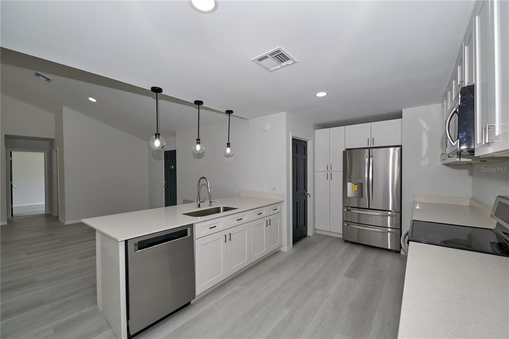 119 Ridgecrest Drive Eustis, FL 32726 - Photo 29 of 52 a open kitchen with stainless steel appliances granite countertop a refrigerator a sink dishwasher a stove and a refrigerator with wooden floor