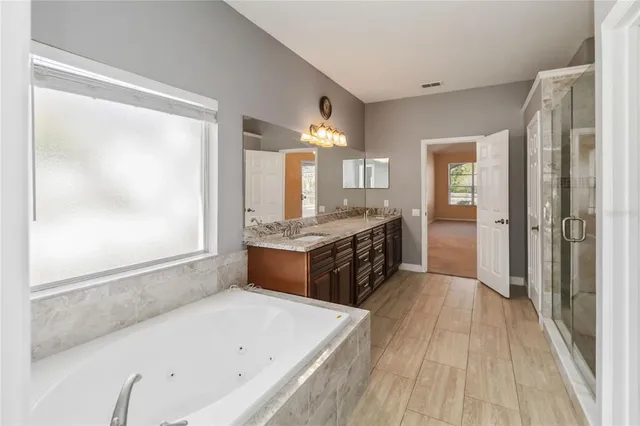 a large bathroom with a tub double vanity sink and a mirror
