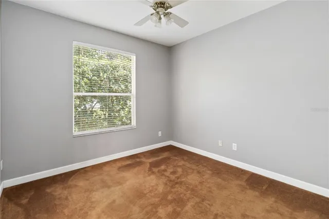 an empty room with a window and a chandelier fan