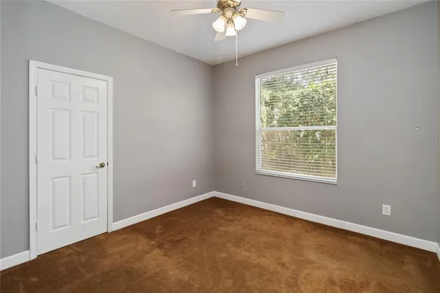 an empty room with a chandelier fan and windows