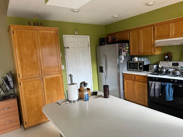 a kitchen with stainless steel appliances granite countertop a refrigerator a stove top oven a sink and dishwasher