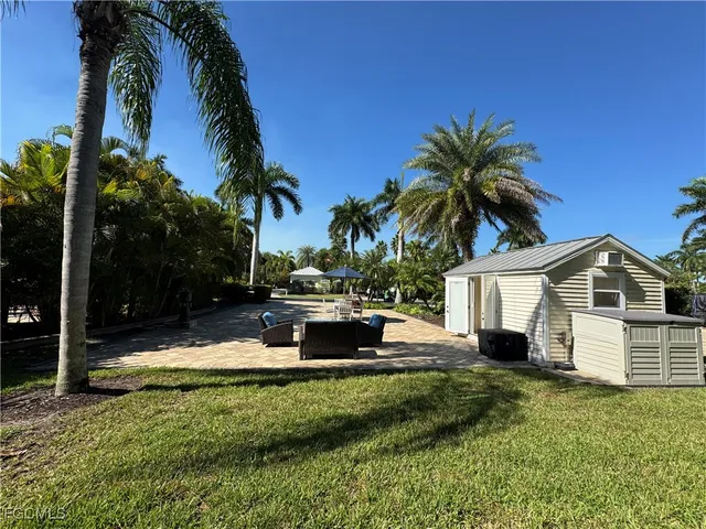 a view of a house with a yard and palm trees