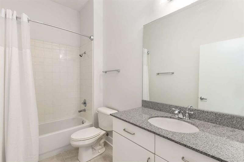384 Ralph McGill Boulevard Northeast, Unit 313 Atlanta, GA 30312 - Photo 14 of 31 a bathroom with a granite countertop sink a toilet a mirror and shower