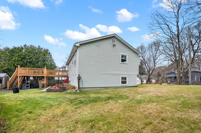 a view of a blue house with a yard and large trees