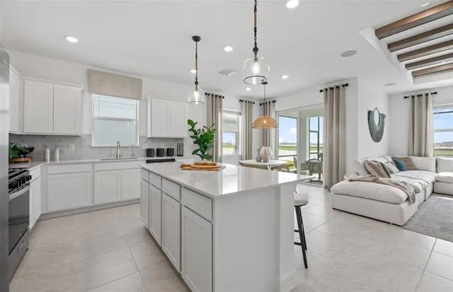 a kitchen with kitchen island granite countertop a sink and white cabinets
