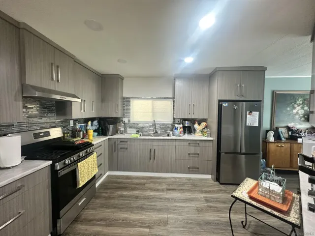 a kitchen with granite countertop a refrigerator stove top oven and sink